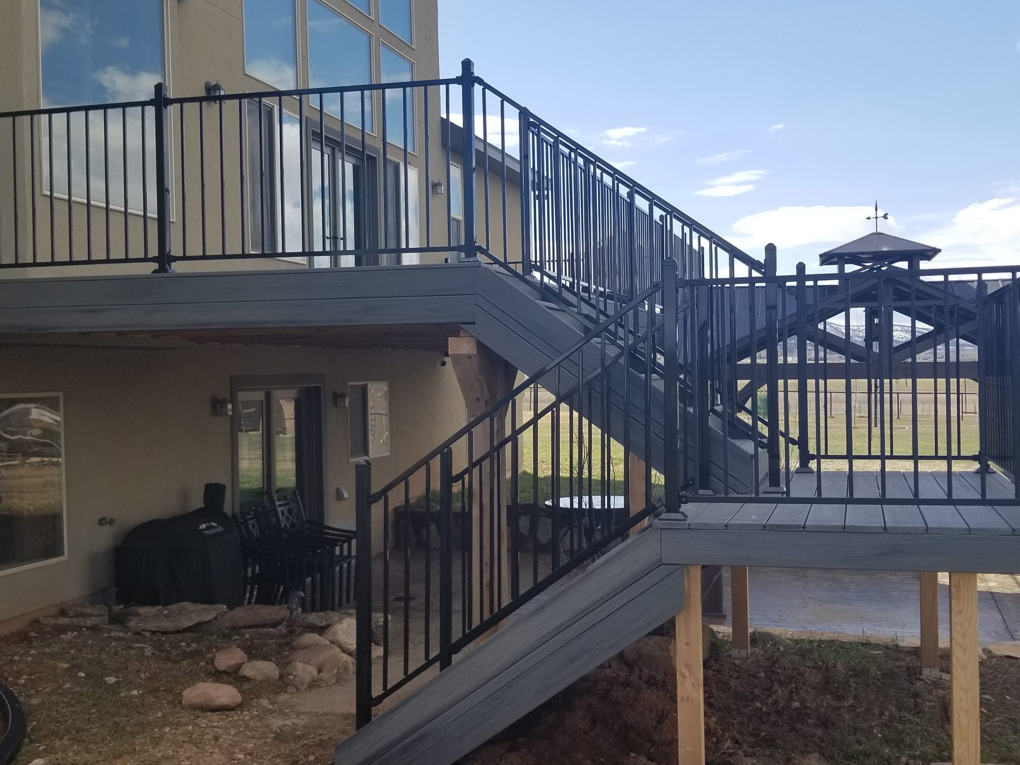 Elevated deck with a landing, stairs, and dark metal railings on an Ellis Property Services project